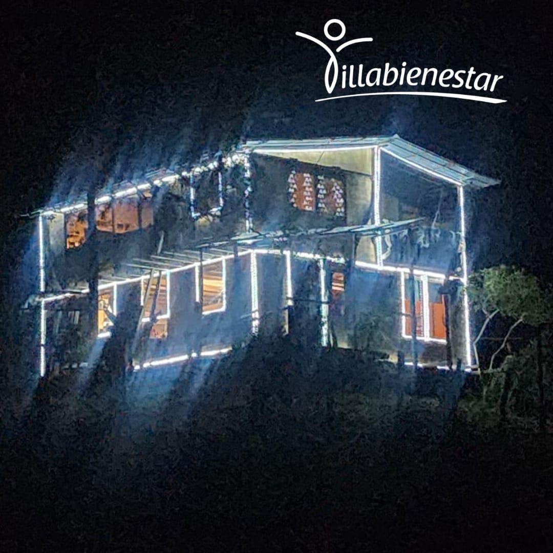 Fachada de Villa Bienestar iluminada de noche