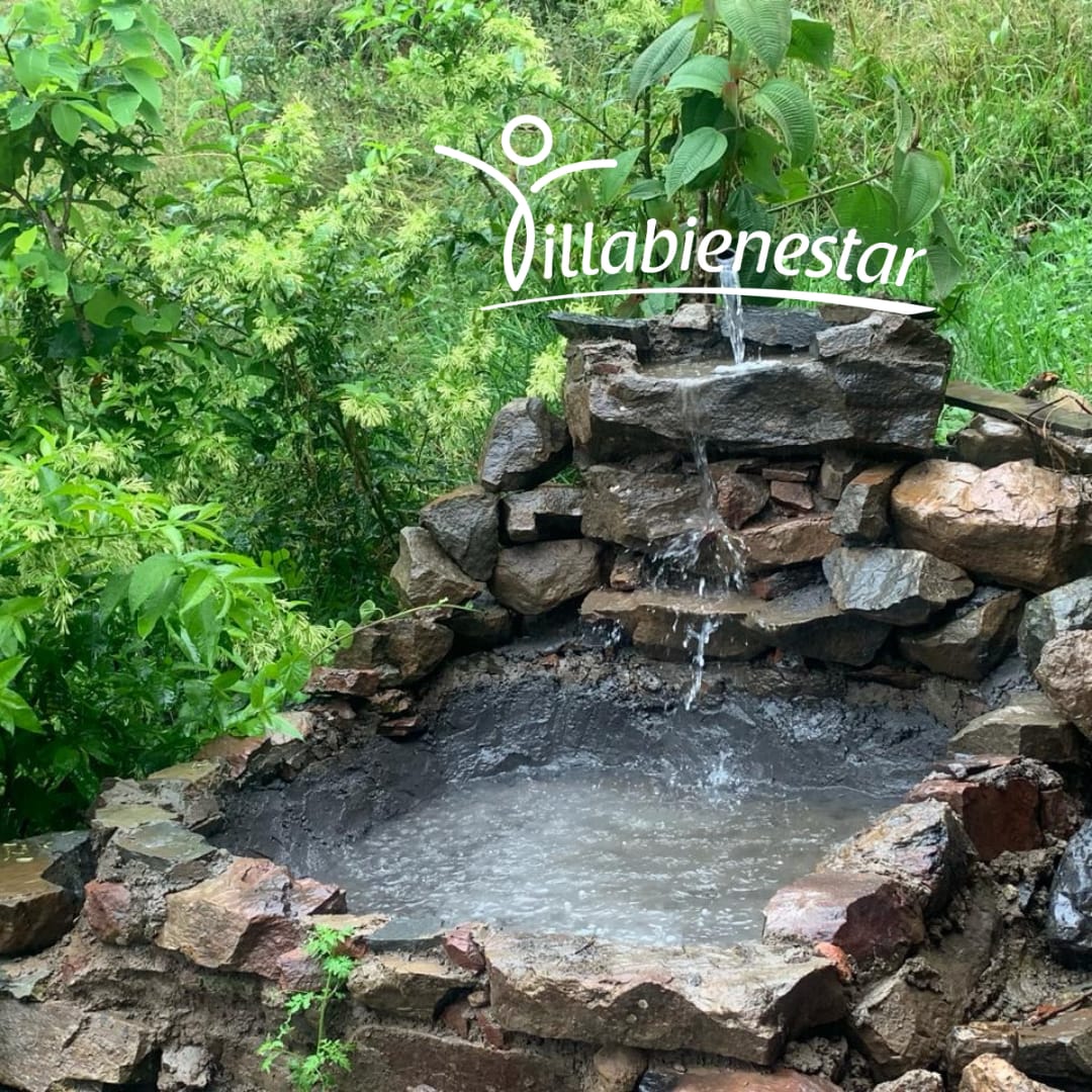 Fuente de piedra con pequeñas cascadas entre la vegetación