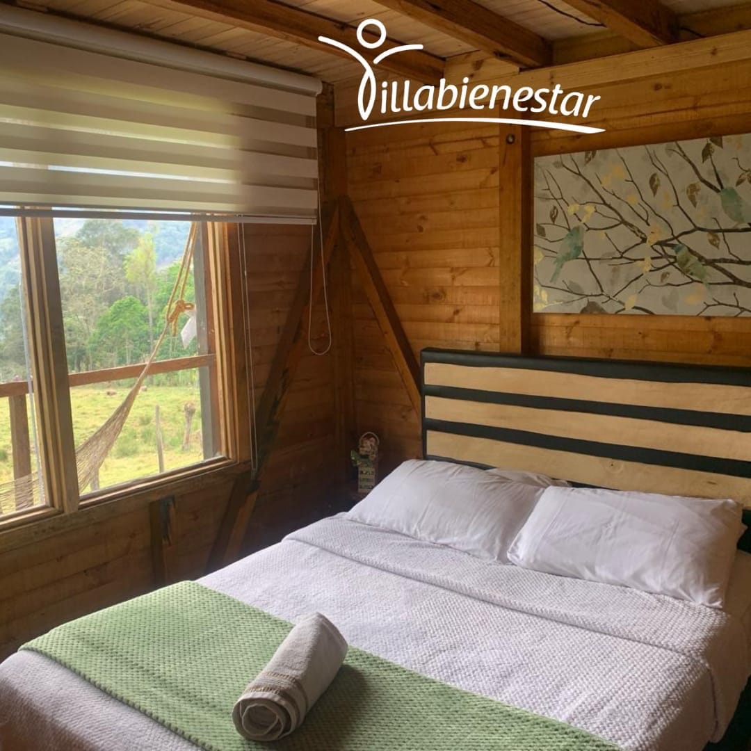 Habitación de madera con cama doble y ventana hacia el jardín